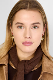 Model met goudkleurige oorbellen met hart en parel