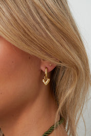 Gouden oorbellen in hartvorm met strass gedragen door model