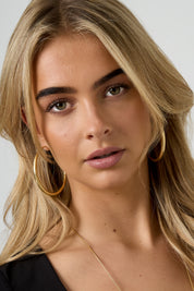 Oorbellen Ringen Uitlopend Goud gedragen door model met blond haar
