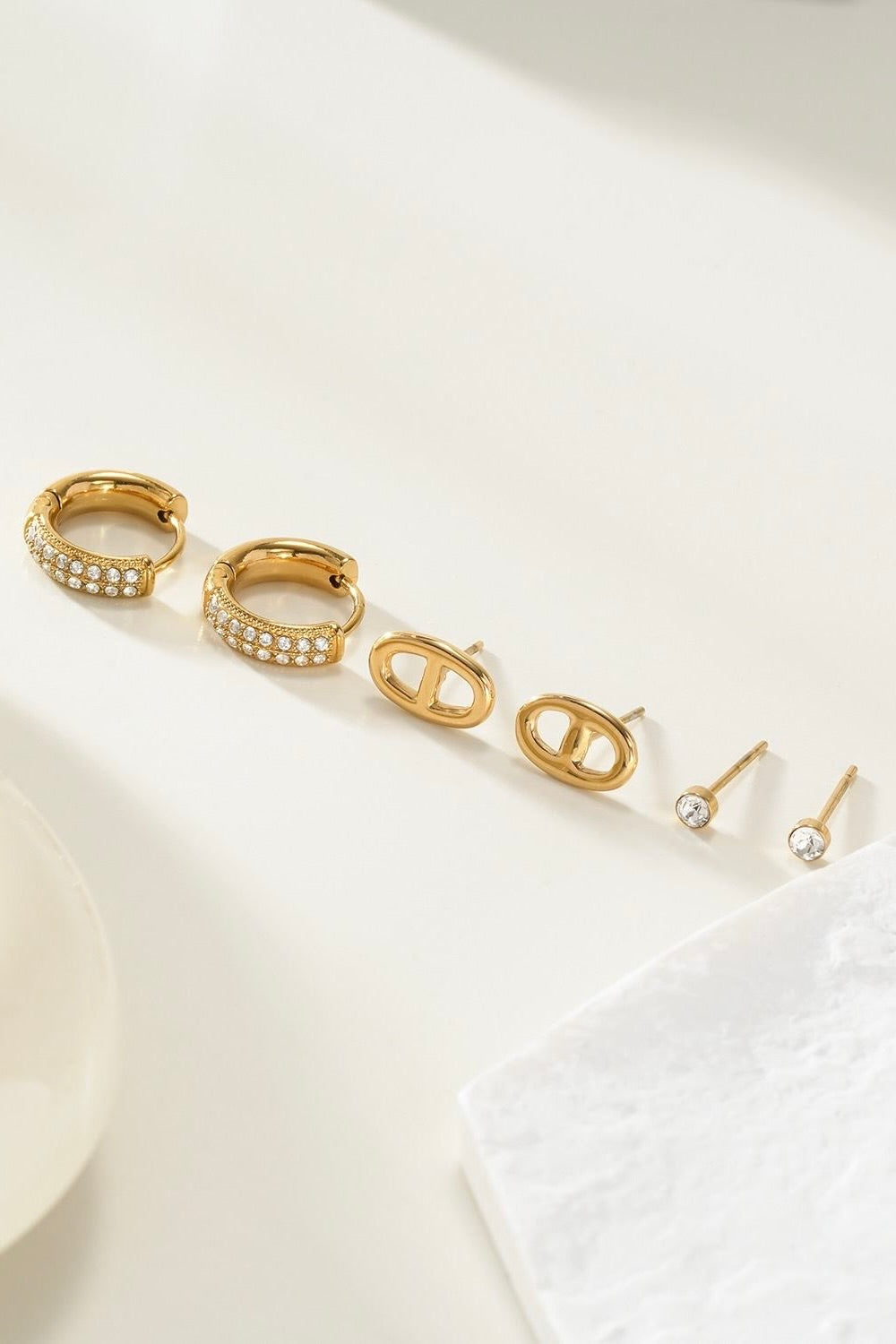 Goudkleurige oorbellen set met drie paar op lichte achtergrond