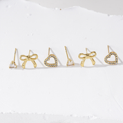 Detail van goudkleurige oorbellen met strikje uit set