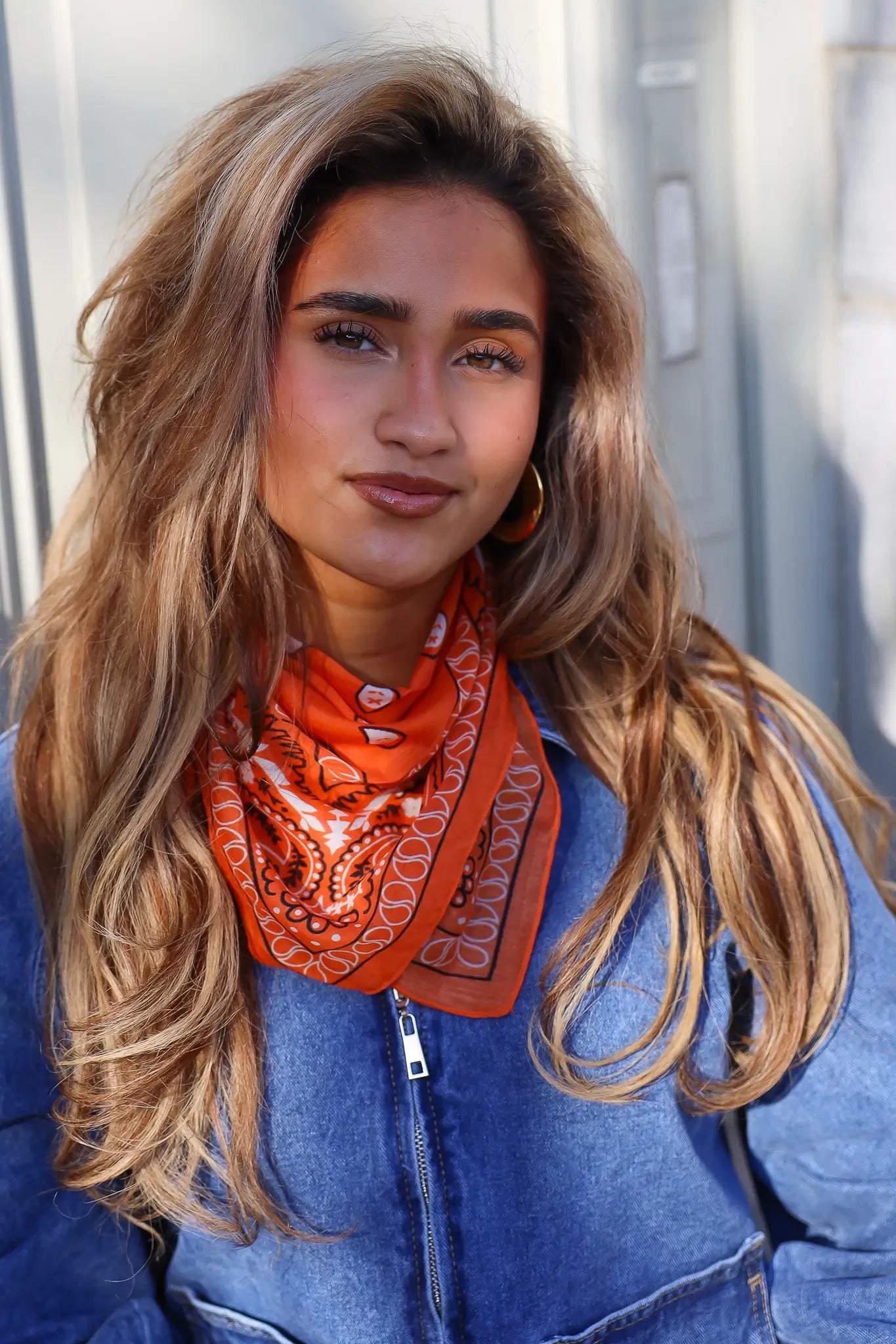 model draagt oranje print sjaaltje dames close up