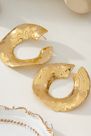 Organische goudkleurige oorringen op lichte achtergrond