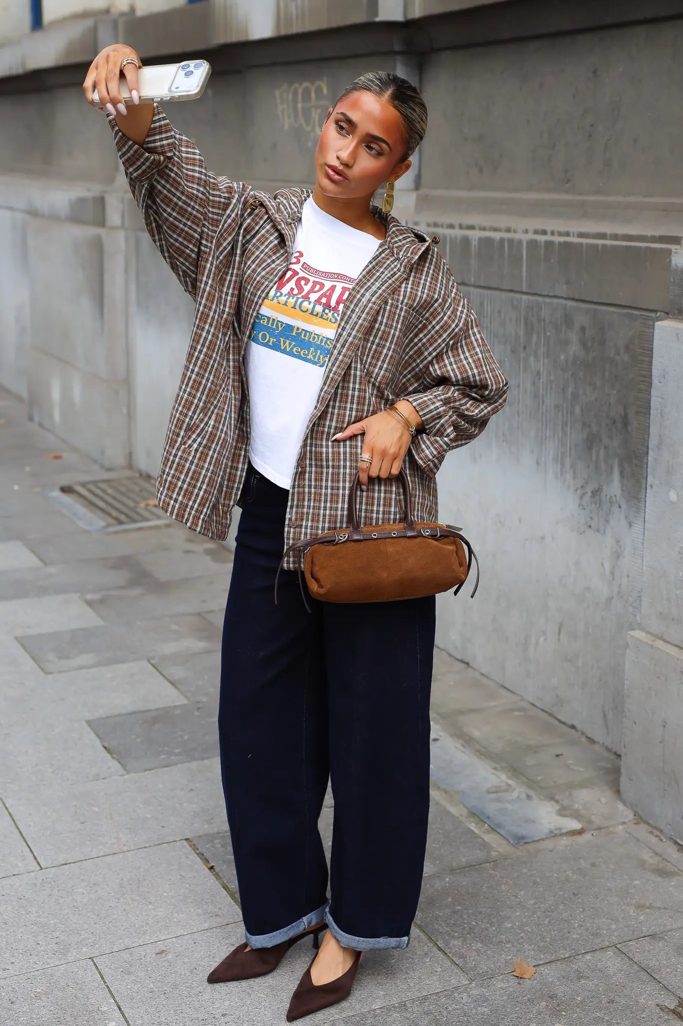 Oversized camel blouse met ruitjes open gedragen over een wit T-shirt met donkere jeans en bruine schoudertas