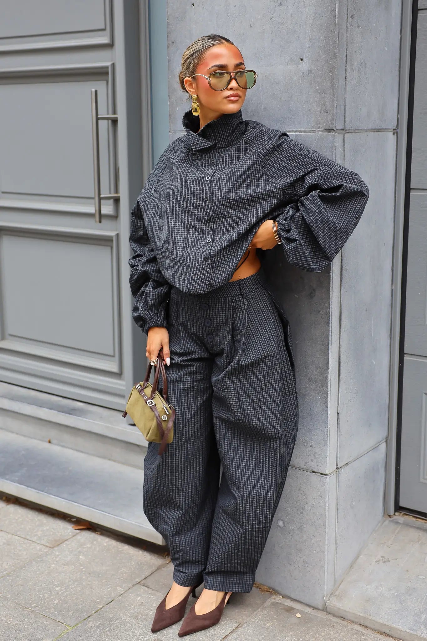 Oversized zwarte windbreaker met subtiele ruitjes ballonmouwen en hoge kraag gecombineerd met een zwarte broek