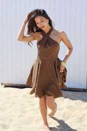 Model loopt met overslag jurk bruin op strand
