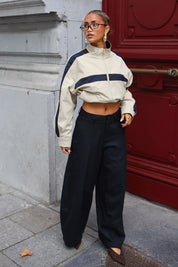 Donkerblauwe wide leg pantalon met hoge taille en soepel vallende broekspijpen gedragen bij een rode deur