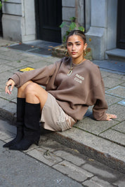 Paris Club Sweater in beige gedragen zittend op straat
