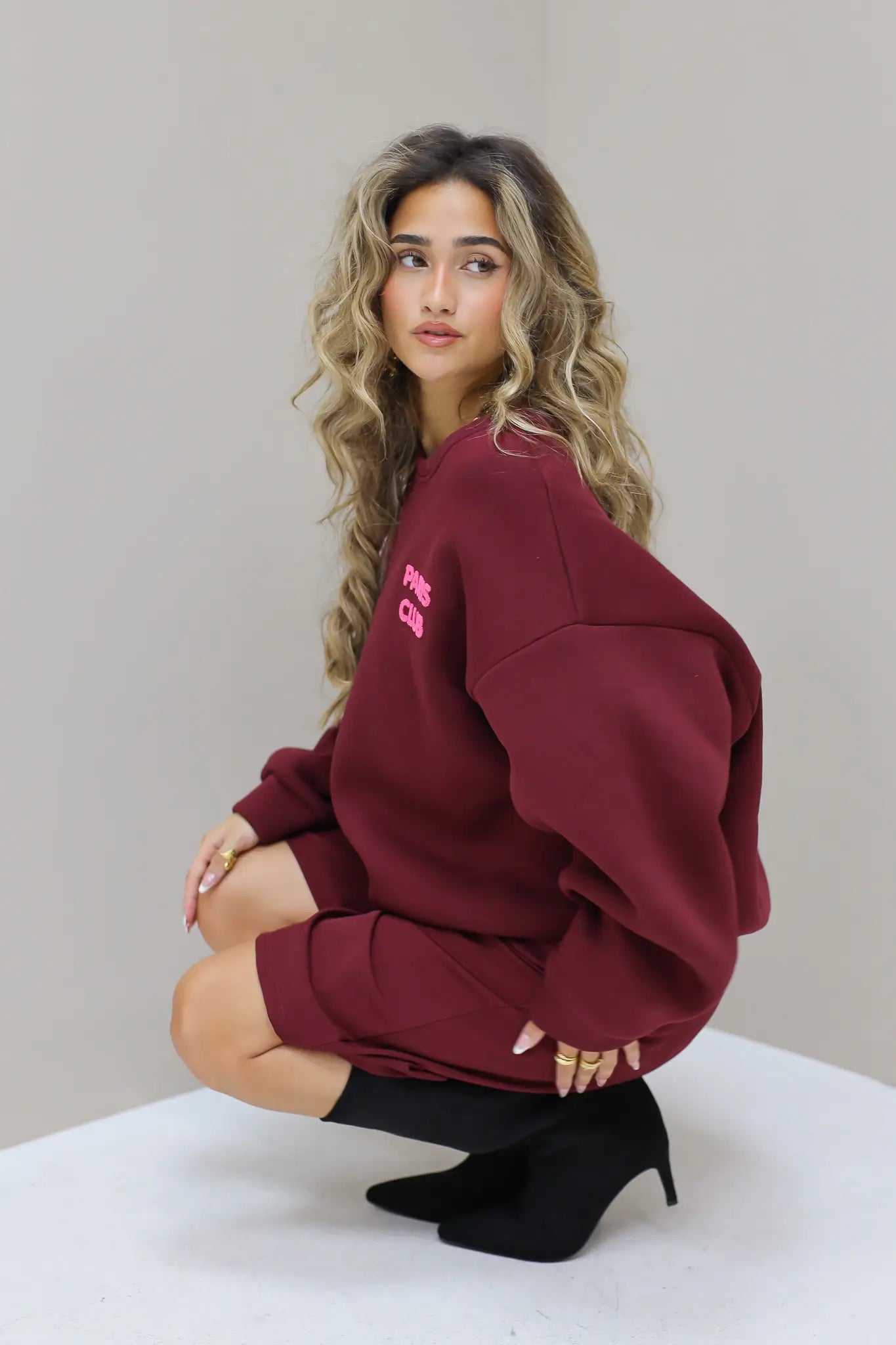Paris Club Sweater in bordeaux zittend in de studio