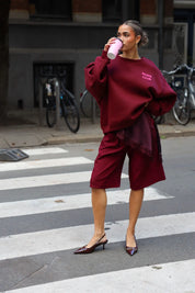 Paris Club Sweater in bordeaux lopend op straat met drankje