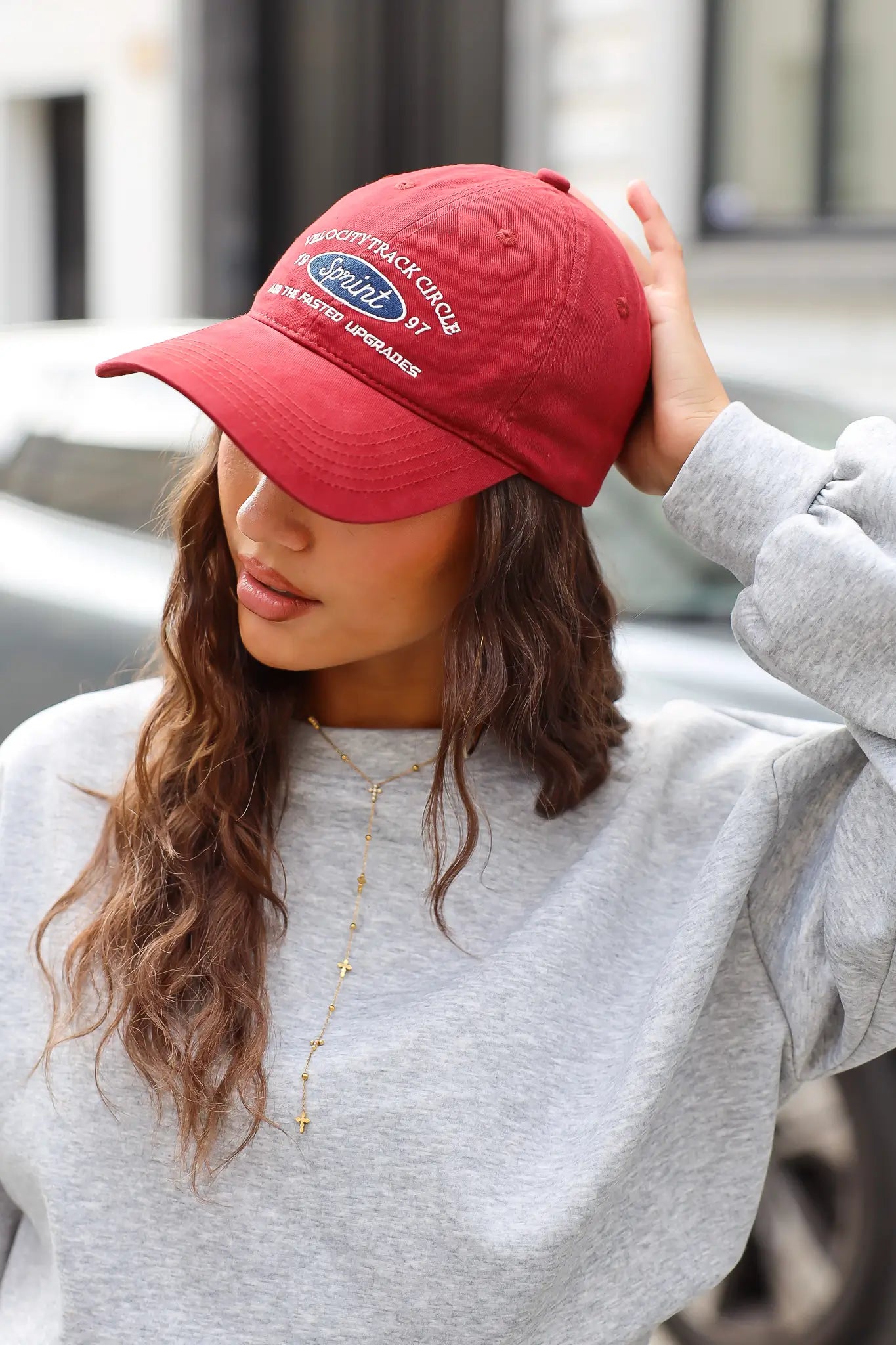 Bordeauxrode Sprint baseball cap met vintage opdruk en gebogen klep gedragen met een grijze sweater