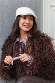 Model met beige pet kijkt recht in camera buiten