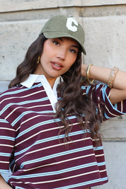 model draagt groene pet dames met gestreepte polo outfit