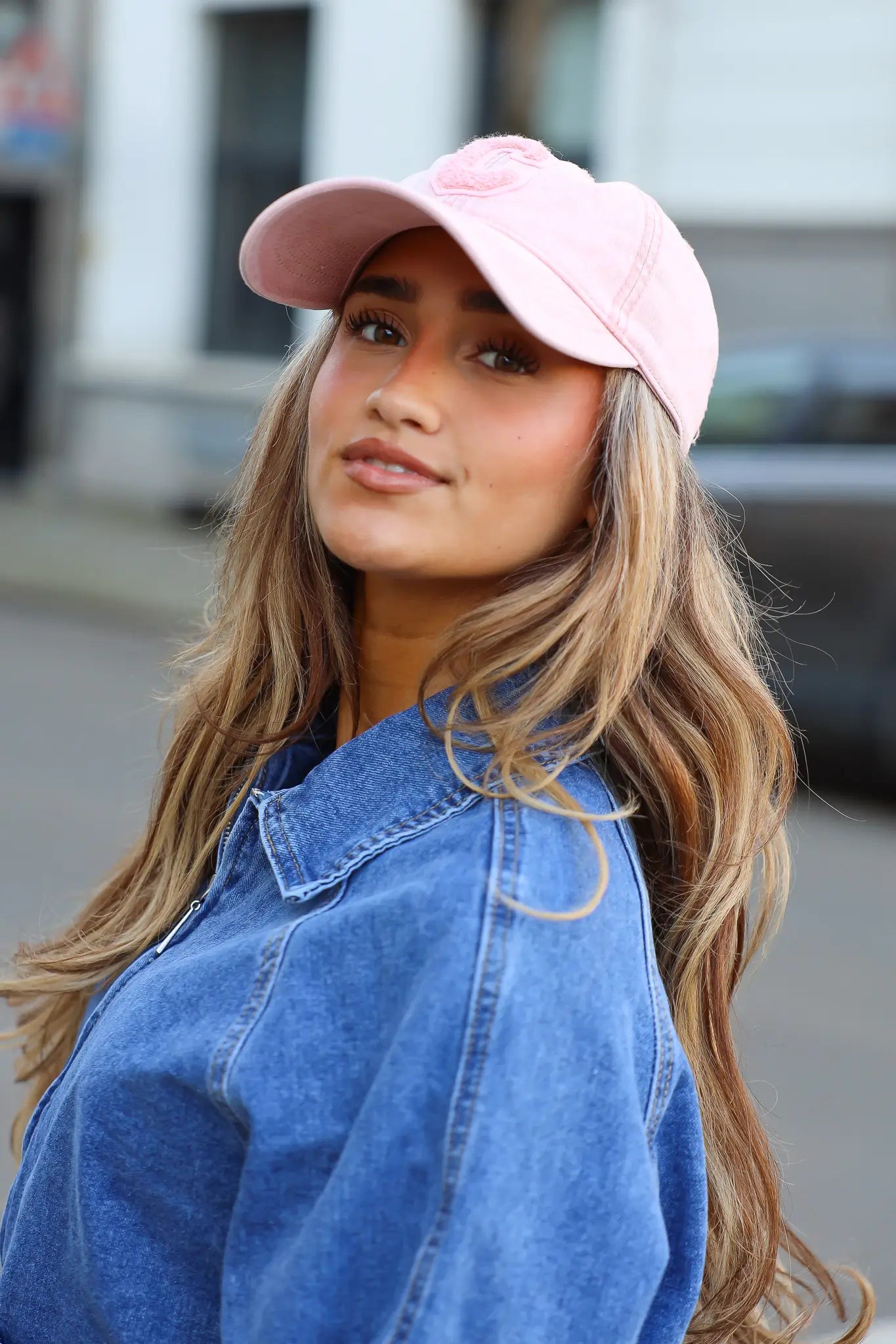 model draagt roze pet dames met denim outfit