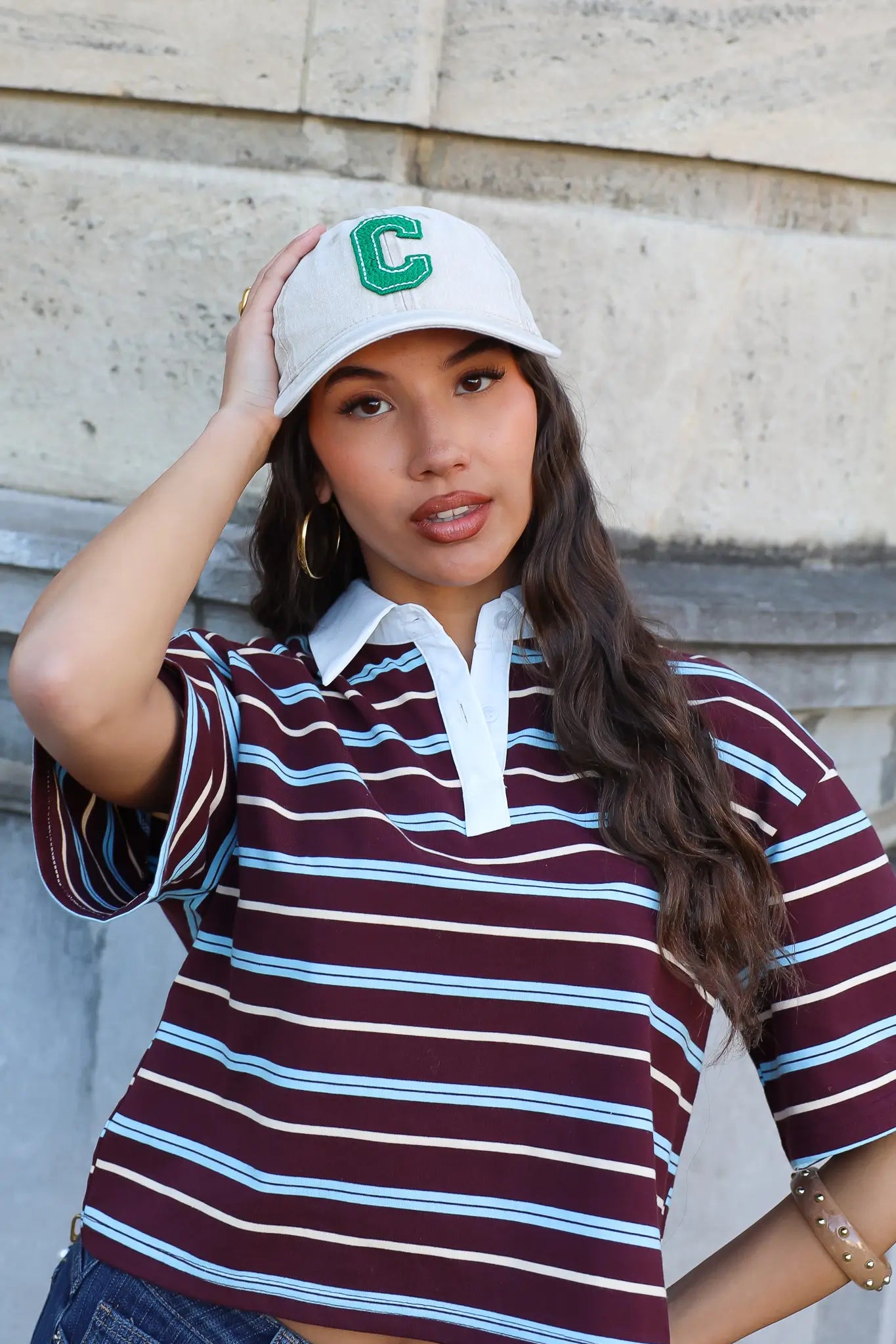 model draagt witte pet dames met gestreepte polo outfit