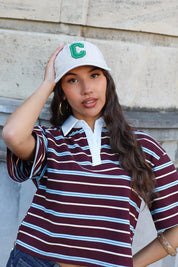 model draagt witte pet dames met gestreepte polo outfit