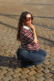 model hurkt met bruin gestreept polo t shirt korte mouwen en jeans