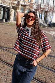 model draagt bruin gestreept polo t shirt met korte mouwen en jeans op straat