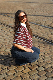 model zit op straat met bruin gestreept polo t shirt korte mouwen