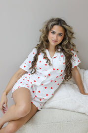 Model zit met opgetrokken knie op bed met kussen naast zich