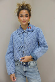 model houdt de knopen van het blauw quilted jasje vast