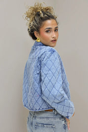 model staat zijwaarts met blauw quilted jasje