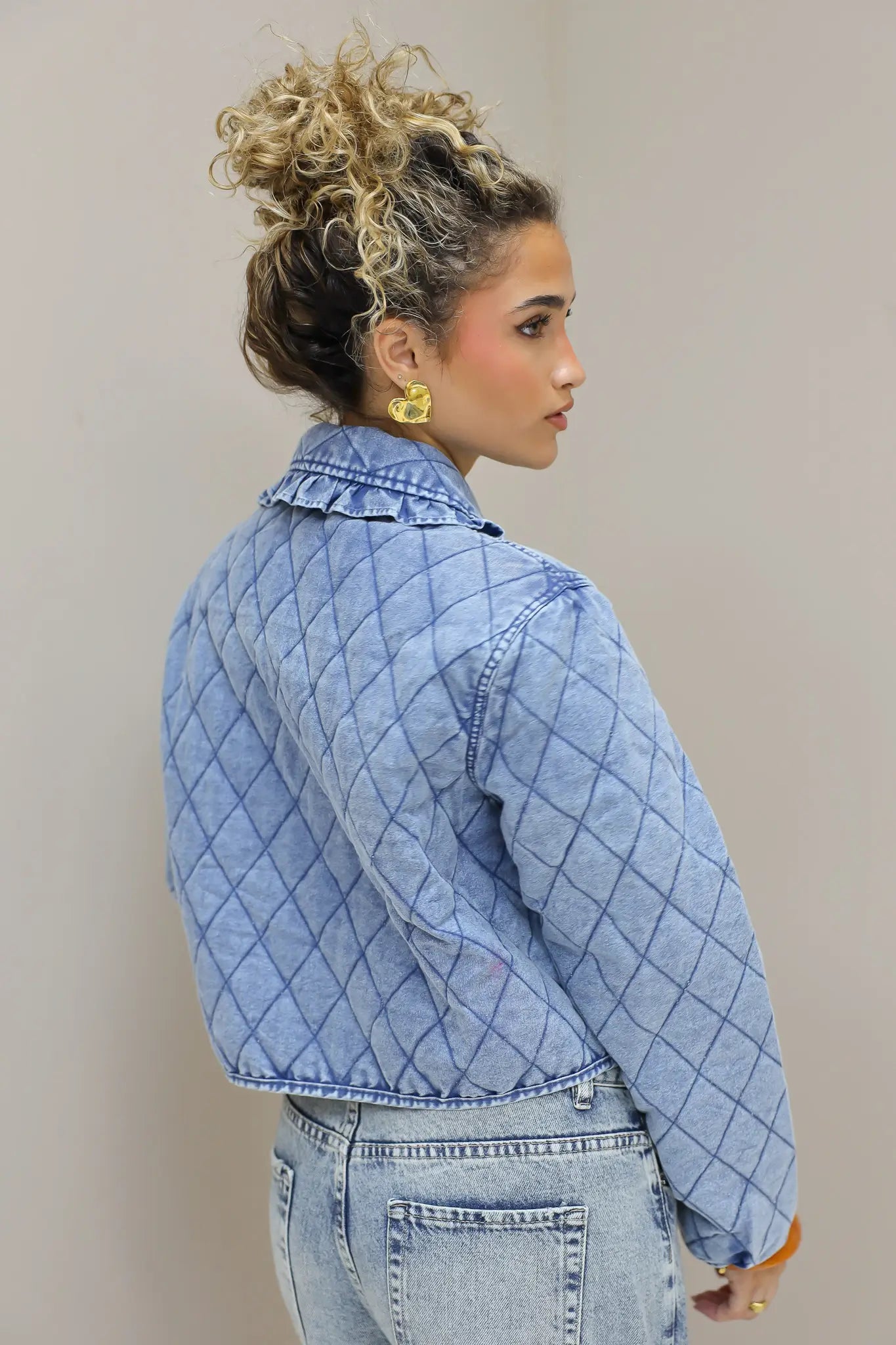 model in studio zijaanzicht met blauw quilted jasje