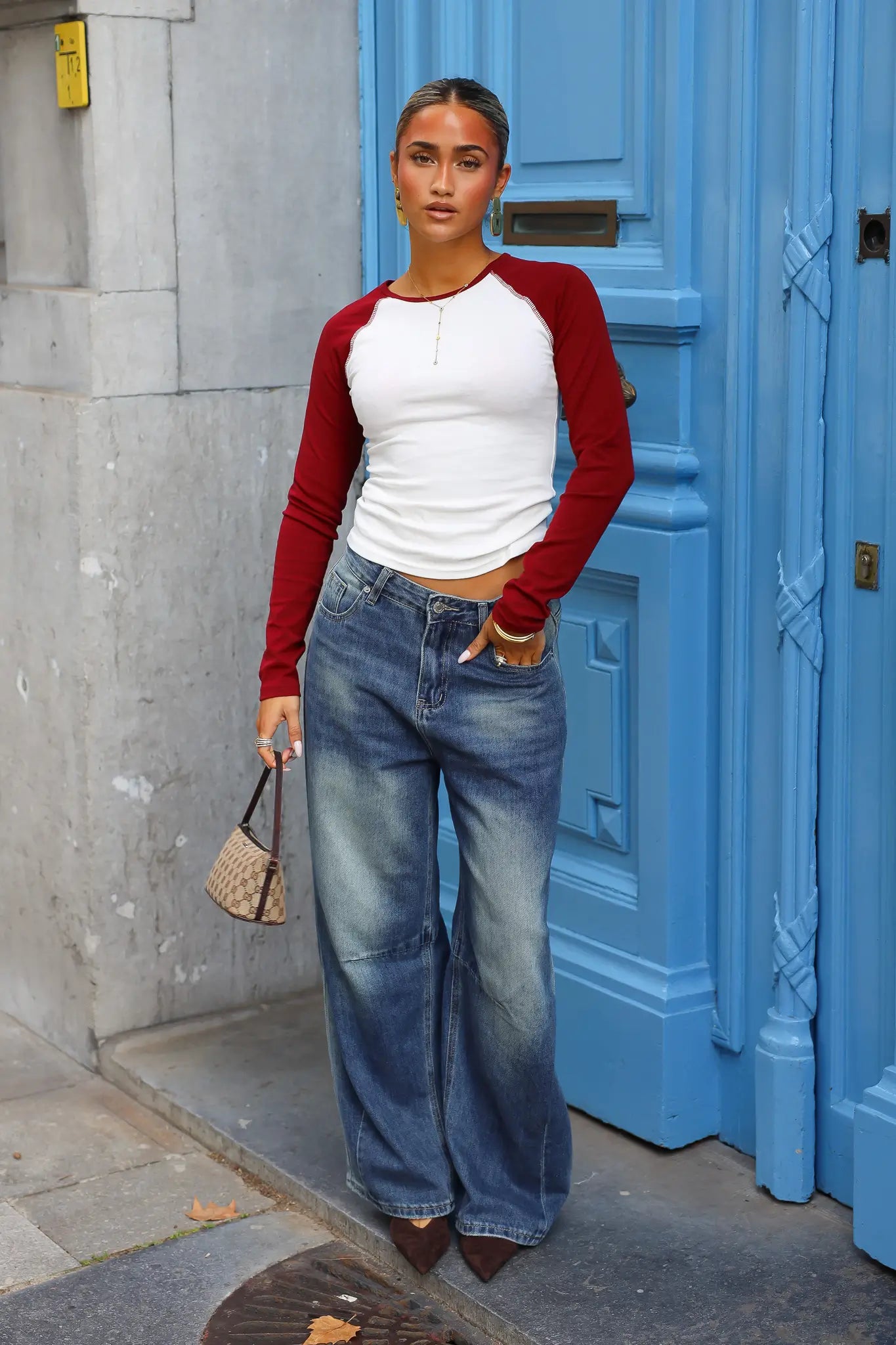 Wit shirt met rode raglanmouwen gecombineerd met blauwe wijde jeans en kleine schoudertas