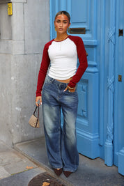 Wit shirt met rode raglanmouwen gecombineerd met blauwe wijde jeans en kleine schoudertas