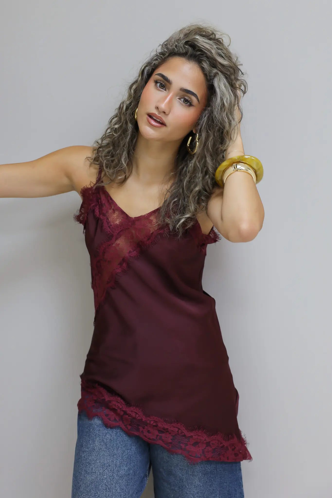 model draagt rode satijnen top met dunne bandjes en kanten rand