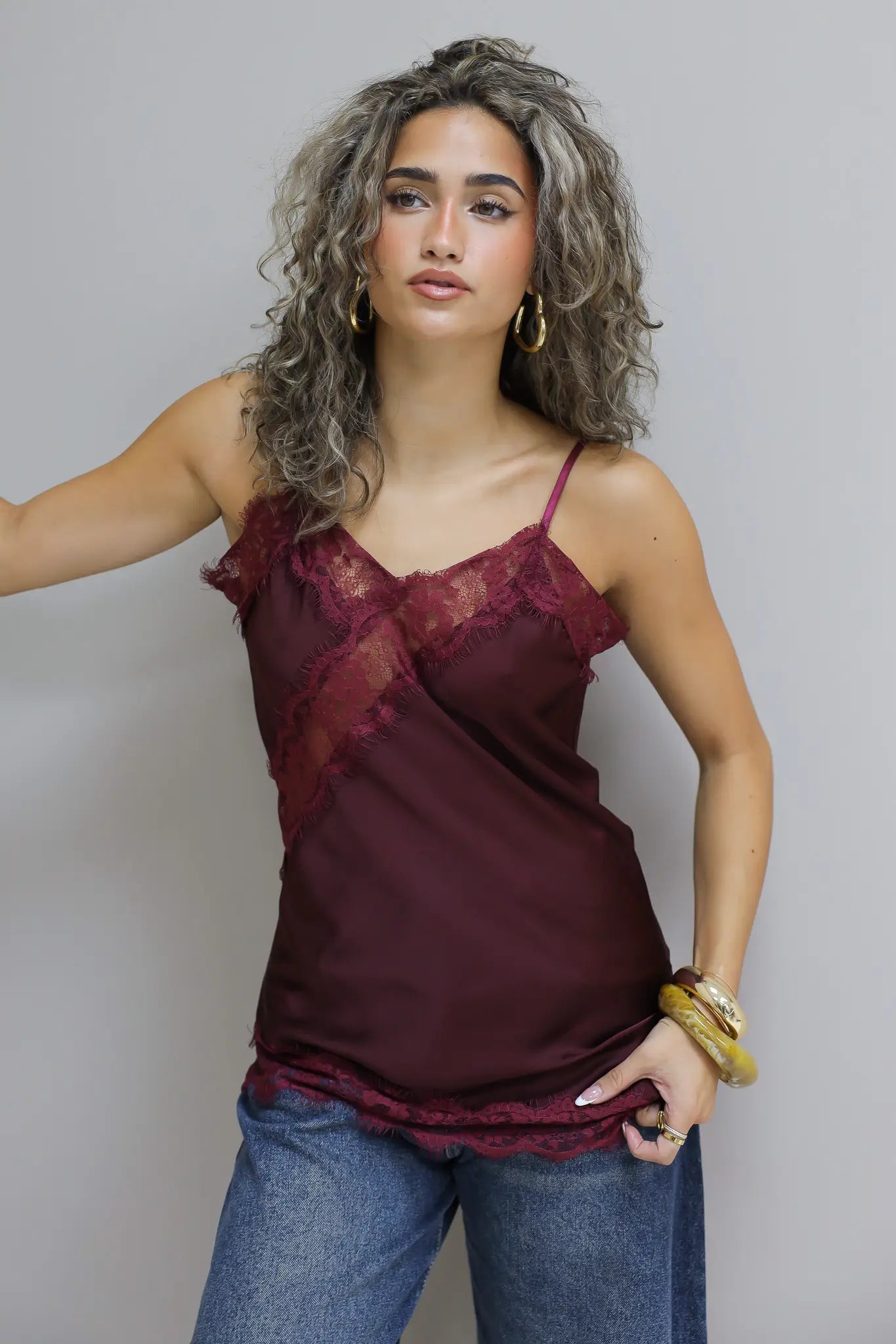 model met rode satijnen top met kanten rand en spijkerbroek