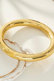 Detail van ronde armband goud om de pols