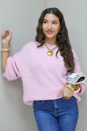 Model draagt roze fluffy trui met blauwe jeans en mok in de hand