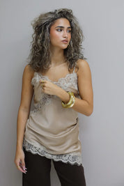 model met satijnen top en kant combineert met bruine broek