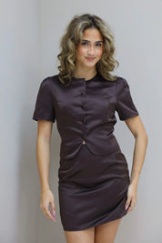 Model met bruine satijnen top met knoopjes, recht vooruit kijkend