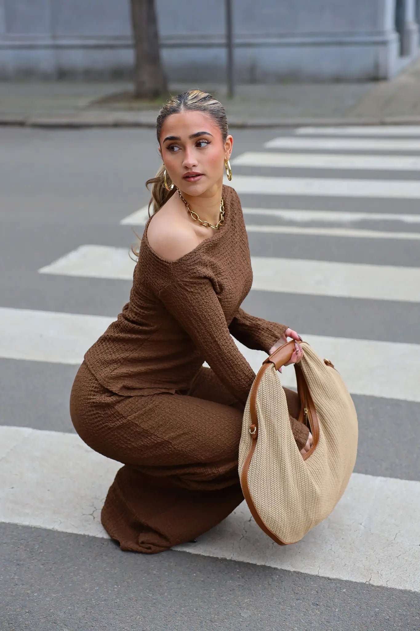 Shopper raffia en leer bruin gedragen terwijl model zit