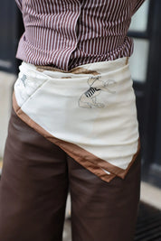 Model draagt witte sjaal met bruine rand als accent bij bruin-witte outfit