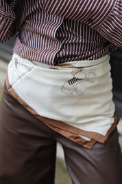 Sjaaltje met bruine rand geknoopt om de taille over een gestreepte blouse