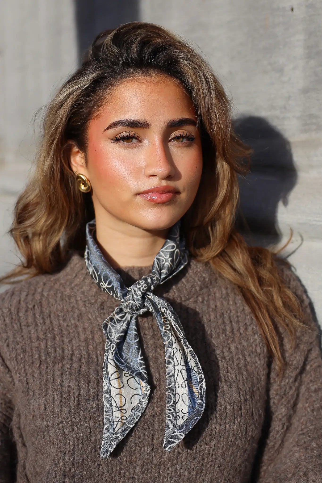 Model draagt handgemaakte grijze sjaal met print om de hals