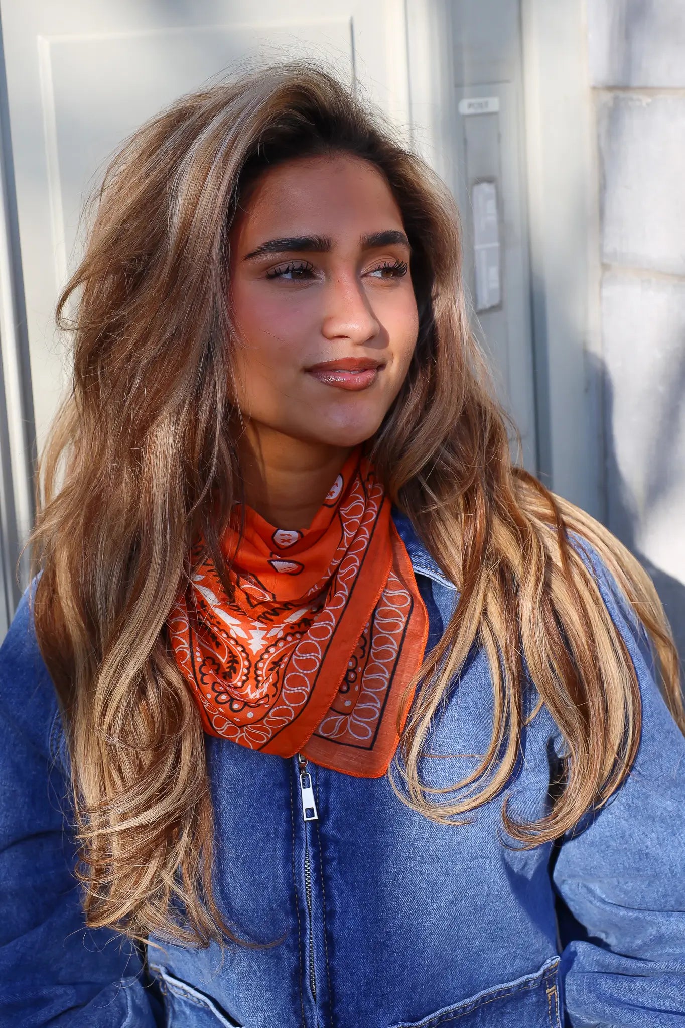 model draagt oranje sjaaltje met print bij denim outfit dames