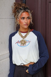 Statement ketting dames goud met bloemvormige hanger en meerdere lagen gecombineerd met een shirt met donkerblauwe mouwen
