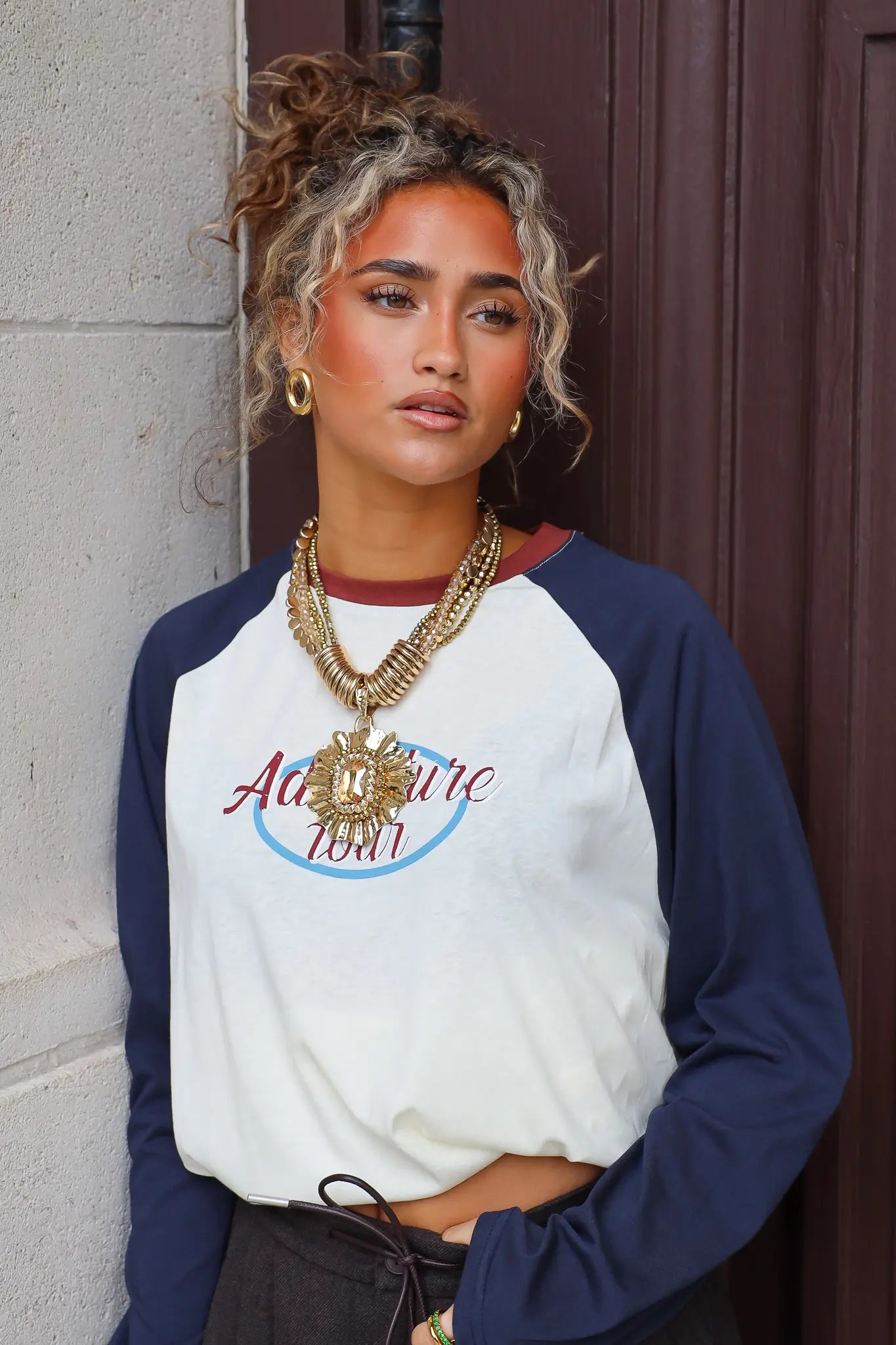 Gouden statement ketting met grote hanger gecombineerd met een wit donkerblauw shirt en donkere broek