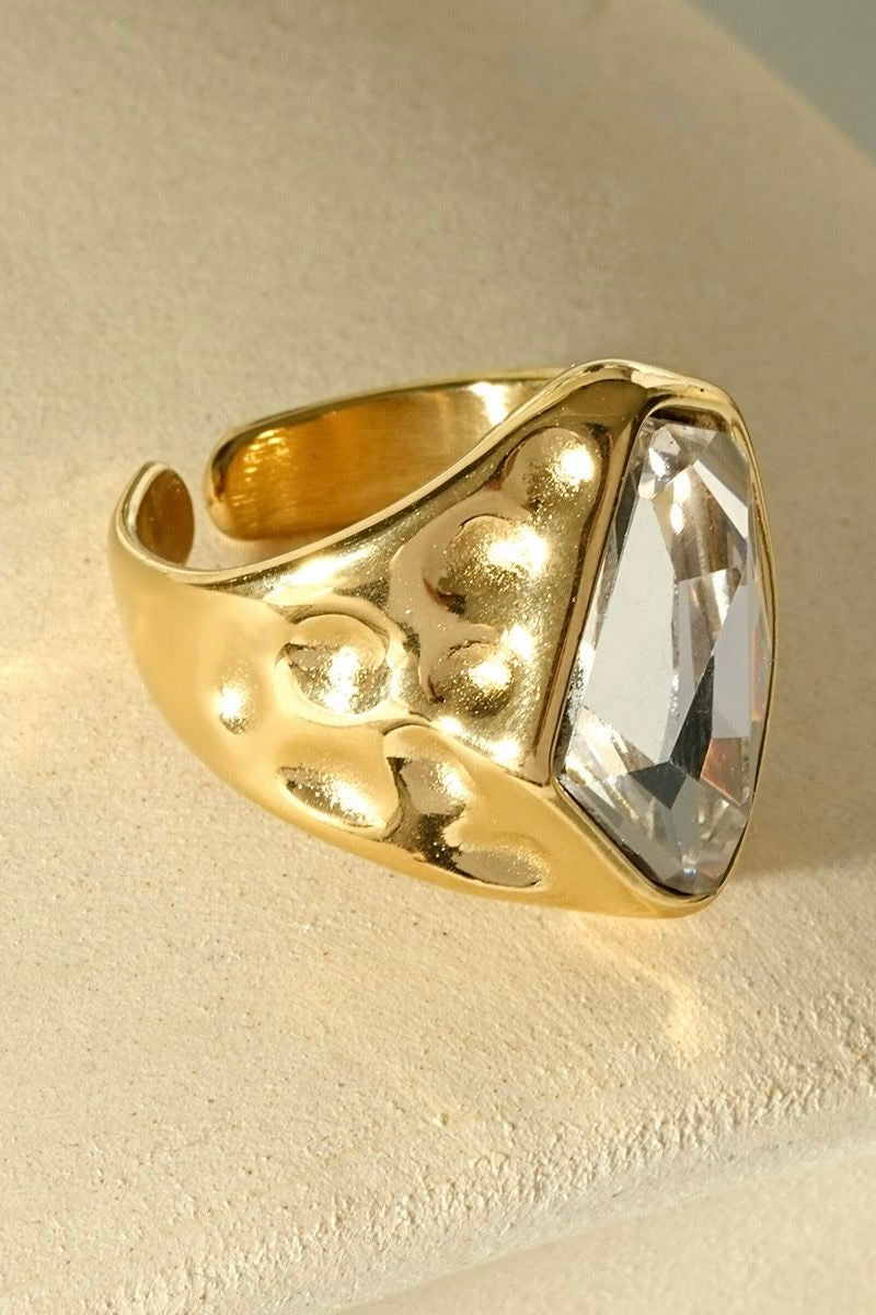 Gouden chunky ring met grote transparante steen en opvallende bolvormige details aan de zijkant