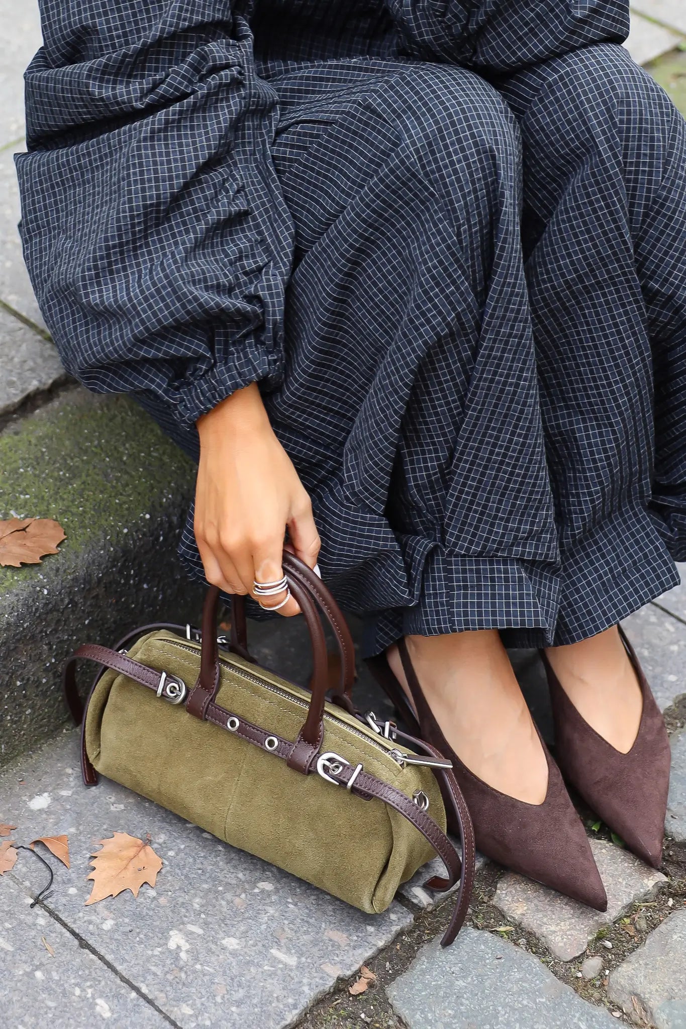 Khaki suède handtas met donkerbruine leren details en zilverkleurige gespen gecombineerd met bruine pumps