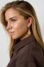 Oorbellen met zonvormige hanger gedragen bij zijaanzicht