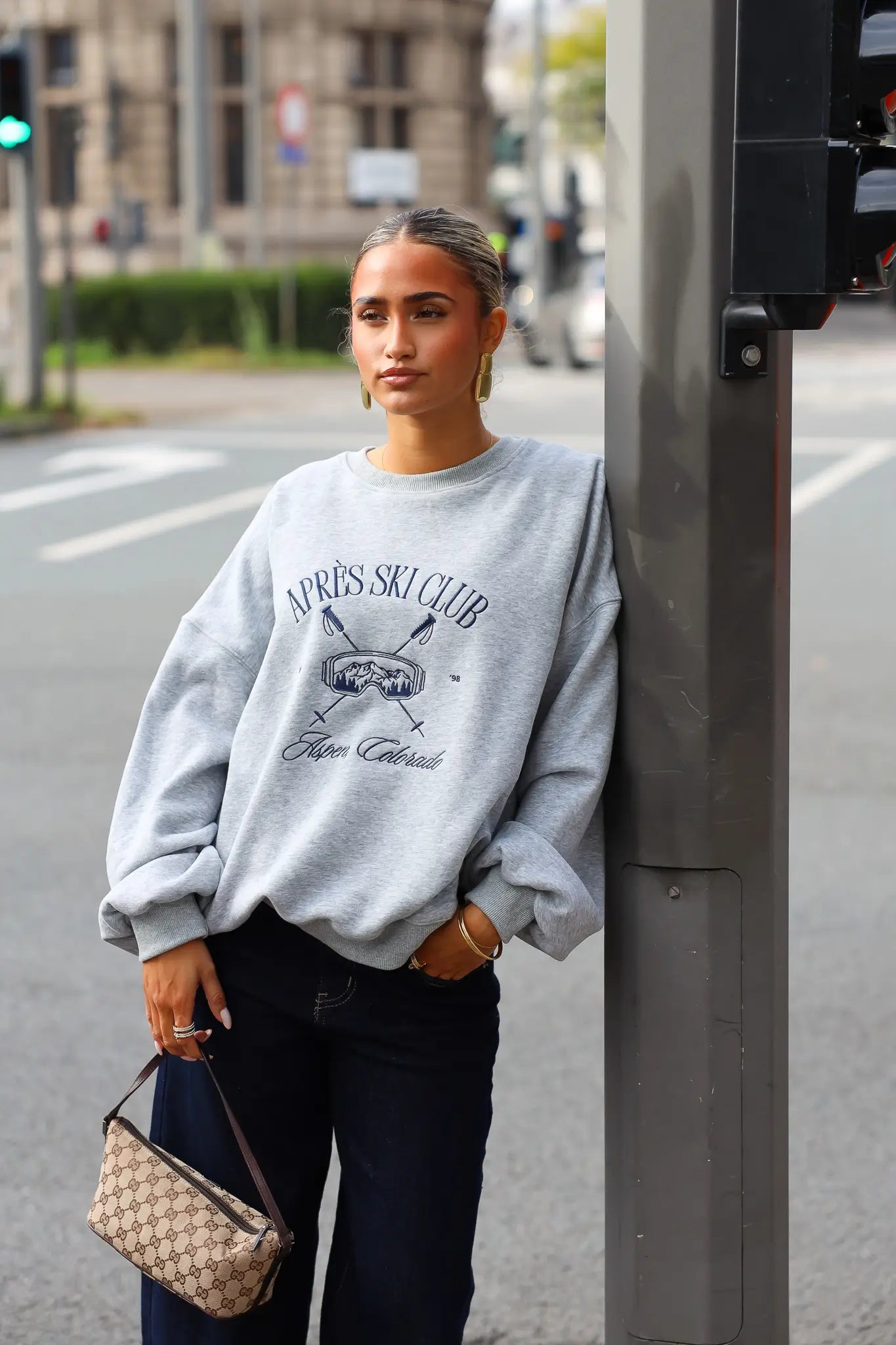 Oversized grijze sweater dames gecombineerd met donkere jeans en een beige handtas