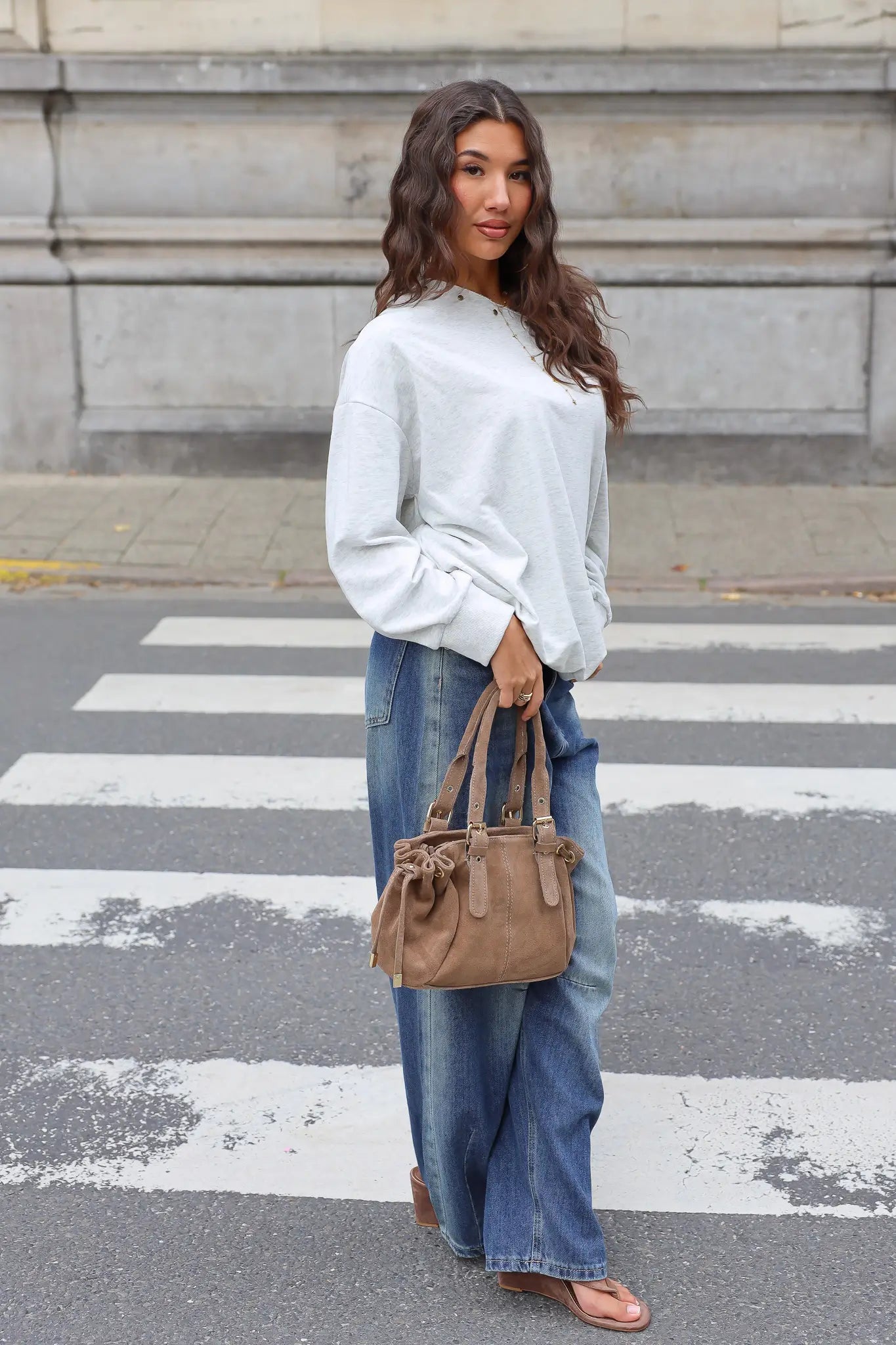 Lichtgrijze oversized sweater gecombineerd met blauwe wide leg jeans