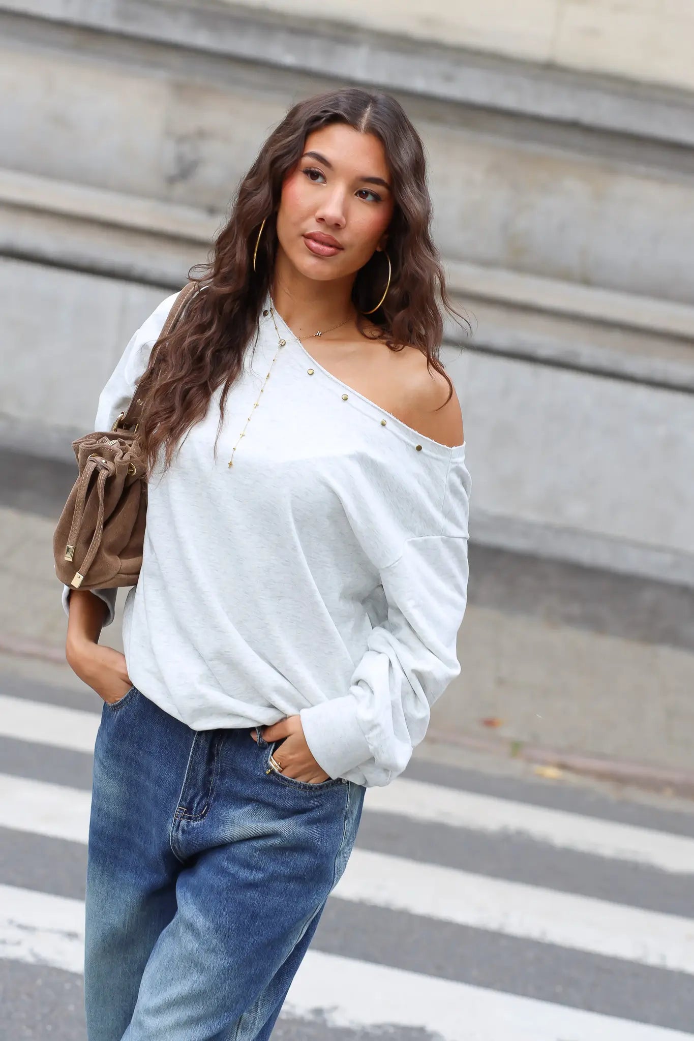 Lichtgrijze off shoulder sweater gedragen met blauwe wide leg jeans