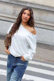 Lichtgrijze off shoulder sweater gedragen met blauwe wide leg jeans