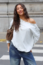 Lichtgrijze off shoulder trui met studs gedragen met een spijkerbroek